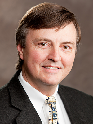 a man wearing a suit and tie smiling at the camera