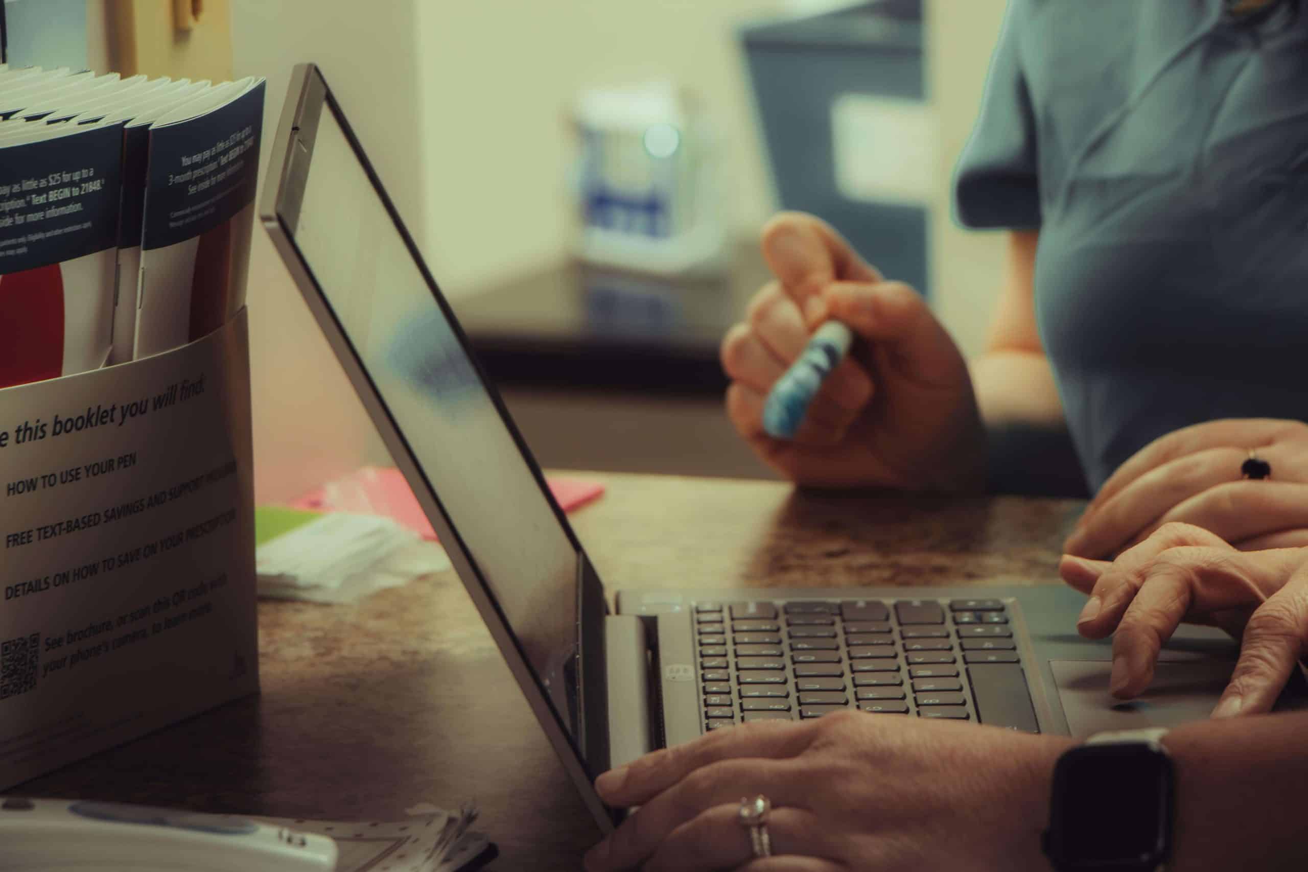 a person using a laptop computer sitting on top of a desk a person using a laptop computer sitting on top of a desk